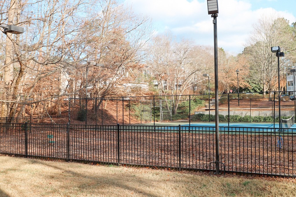 a tennis court with a fence in front of a pool at The Crest at Berkeley Lake, Duluth