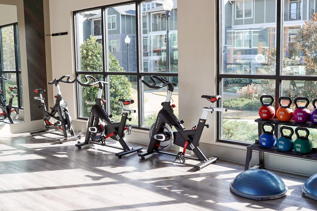 a gym with exercise bikes and weights in front of a window
