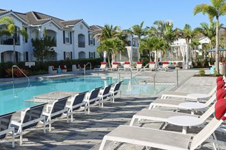 The Crest at Naples Luxury Swimming Pool Seating a large swimming pool with white chairs and palm trees