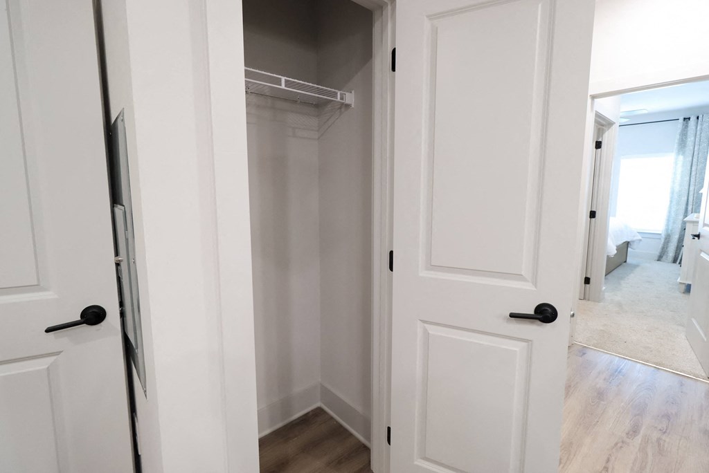 a walk in closet with white doors and a white closet door open to a bedroom at The Crest at South Point Apartments, Davenport , GA
