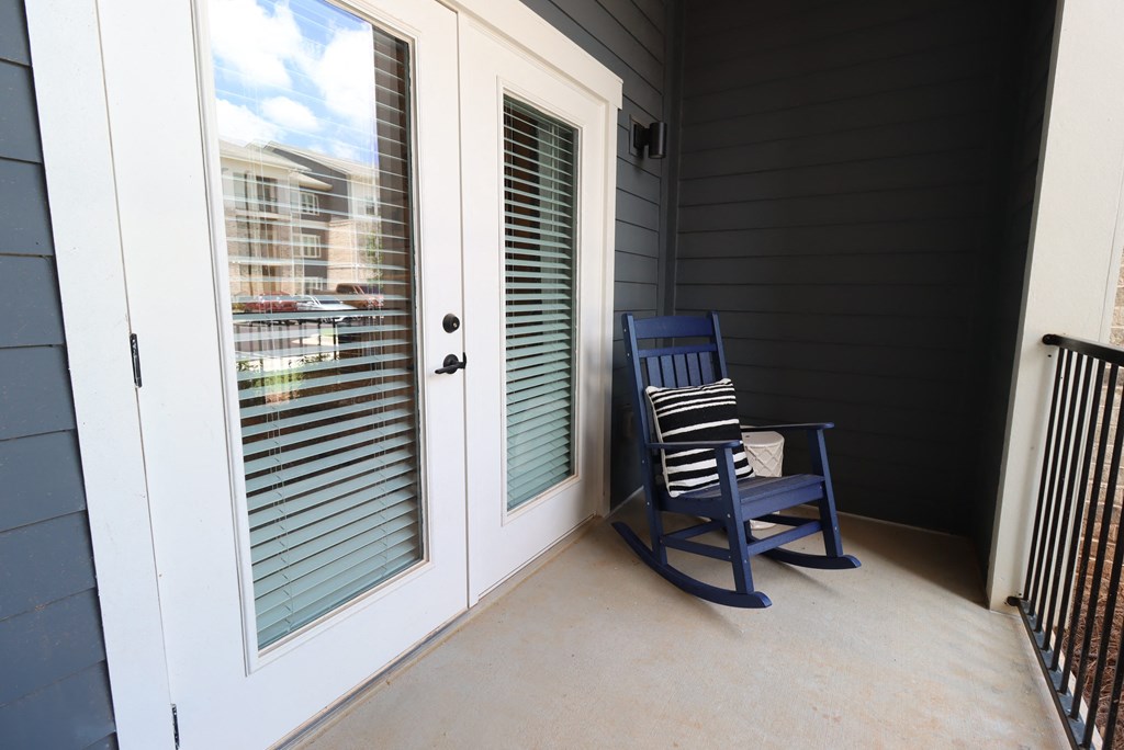 a rocking chair on a porch next to a door at The Crest at South Point Apartments, Georgia, 30253