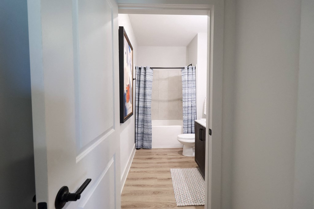 a hallway with a door to a bathroom with a shower and a toilet at The Crest at South Point Apartments, Georgia