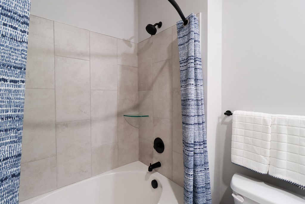 a bathroom with a shower and a toilet and a tub at The Crest at South Point Apartments, Georgia, 30253