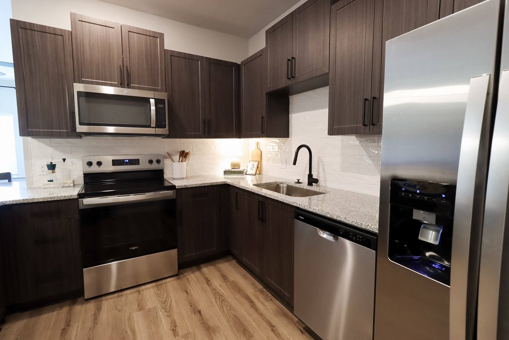 a kitchen with stainless steel appliances and dark wood cabinets at The Crest at South Point Apartments, Georgia, 30253
