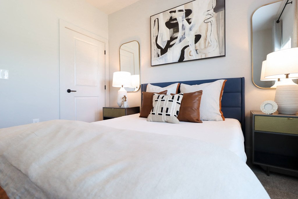 a bedroom with a bed and two lamps and a painting on the wall at The Crest at South Point Apartments, Georgia