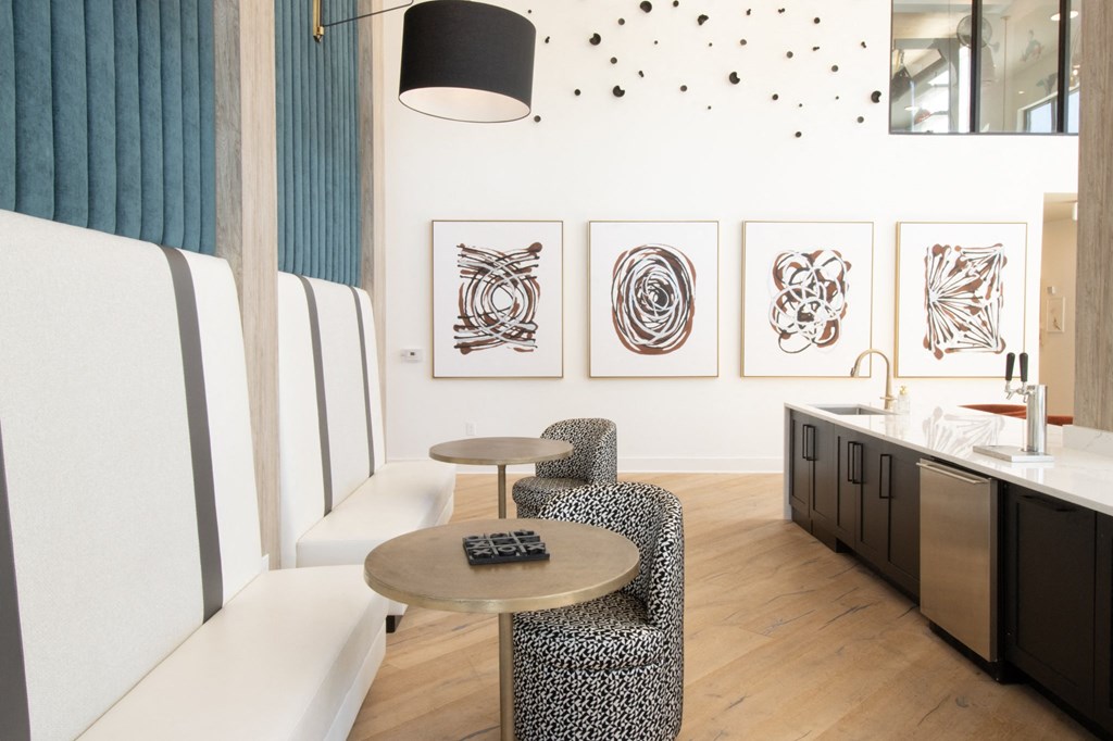 a seating area with a table and chairs and paintings on the wall at The Wren Apartments, Lawrenceville, Georgia