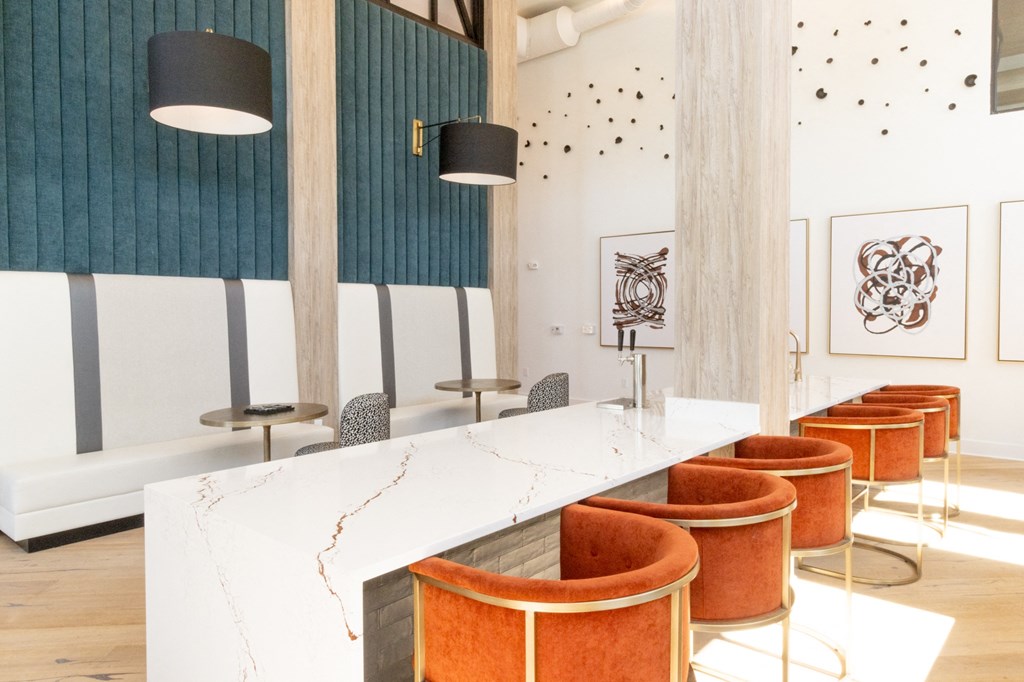 a communal table with orange chairs and a marble counter top in a restaurant at The Wren Apartments, Georgia, 30043