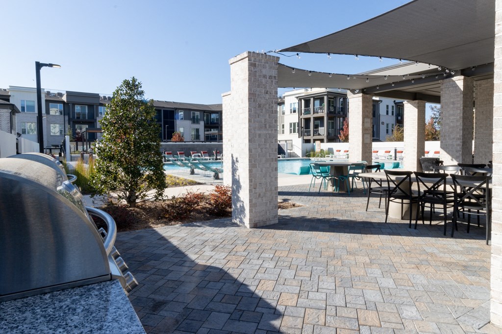 a patio with tables and chairs and a swimming pool at The Wren Apartments, Lawrenceville, GA, 30043
