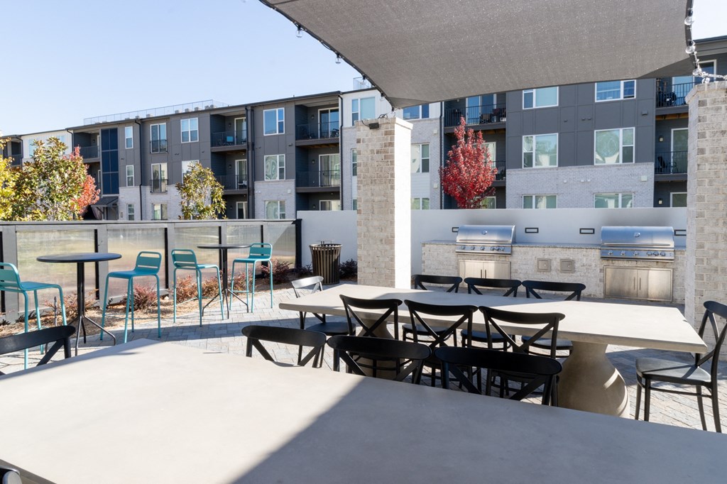an outdoor patio with tables and chairs at an apartment building at The Wren Apartments, Georgia, 30043