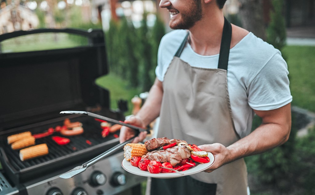 a man holding a plate of food in front of a grill at The Crest at South Point, McDonough, 30253