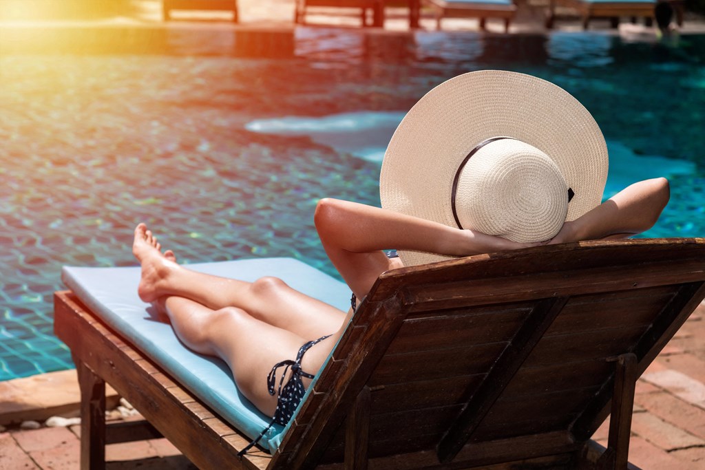 a woman in a straw hat lies on a chaise lounge by a pool at The Crest at South Point, Georgia