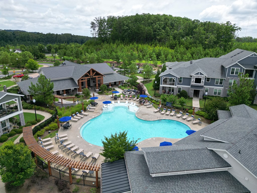 an aerial view of a resort style pool with lounge chairs and umbrellas
