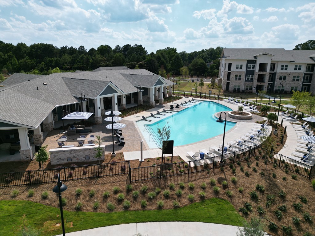 A large outdoor swimming pool surrounded by a black fence and a building in the background. at The Crest at South Point Apartments, Davenport , Georgia