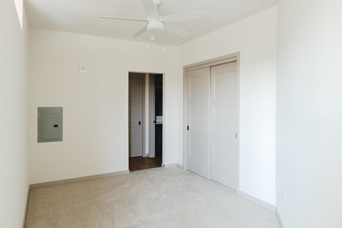 an empty living room with white walls and a ceiling fan