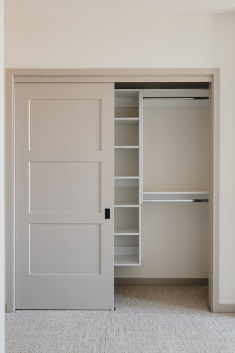 an open bedroom closet with a white door and shelves