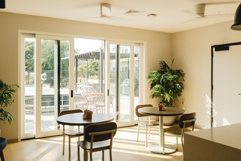 a living room with tables and chairs and sliding glass doors
