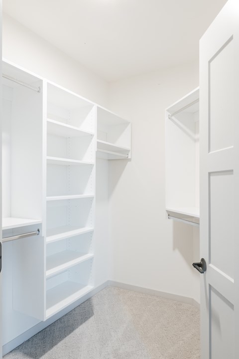 a small closet with white shelves and a white door