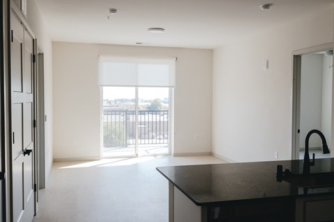 an empty living room with a door to a balcony