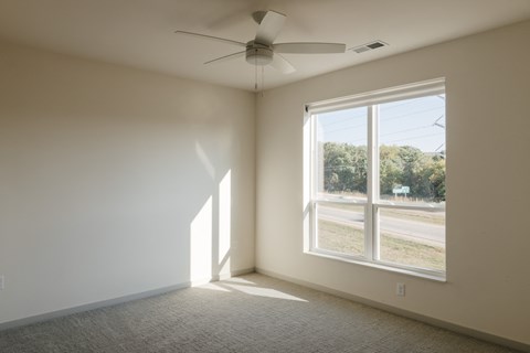 an empty room with a large window and a ceiling fan