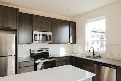 a kitchen with white countertops and black cabinets and a window