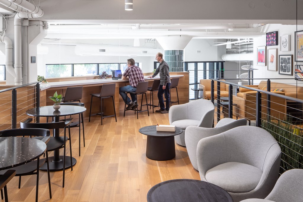 two men standing at a bar in a room with chairs and tables