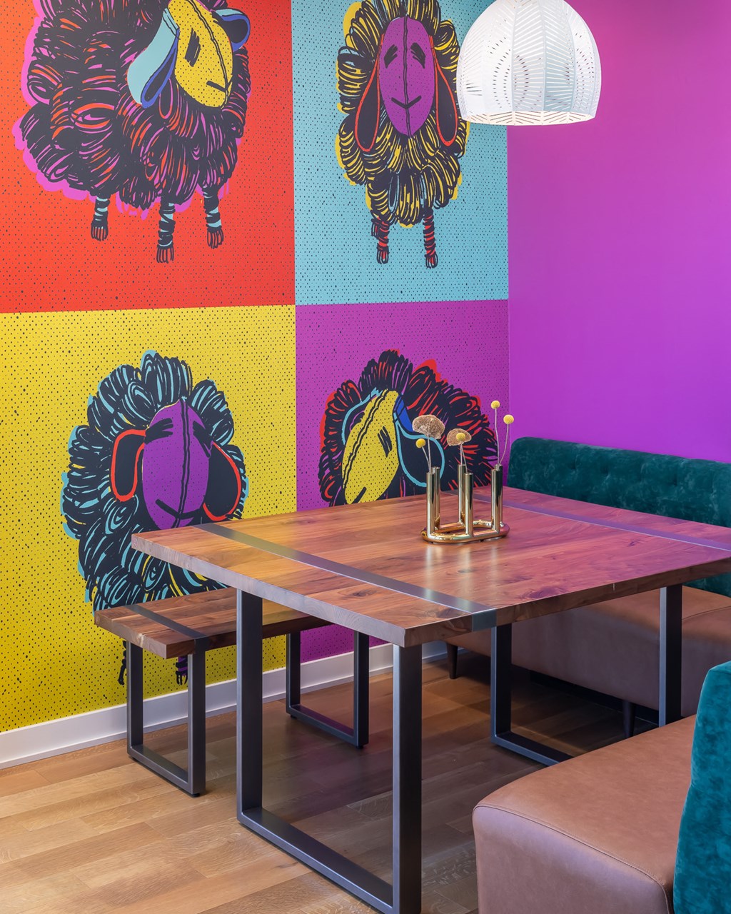 a dining room with a table and chairs and a wall with colorful paintings