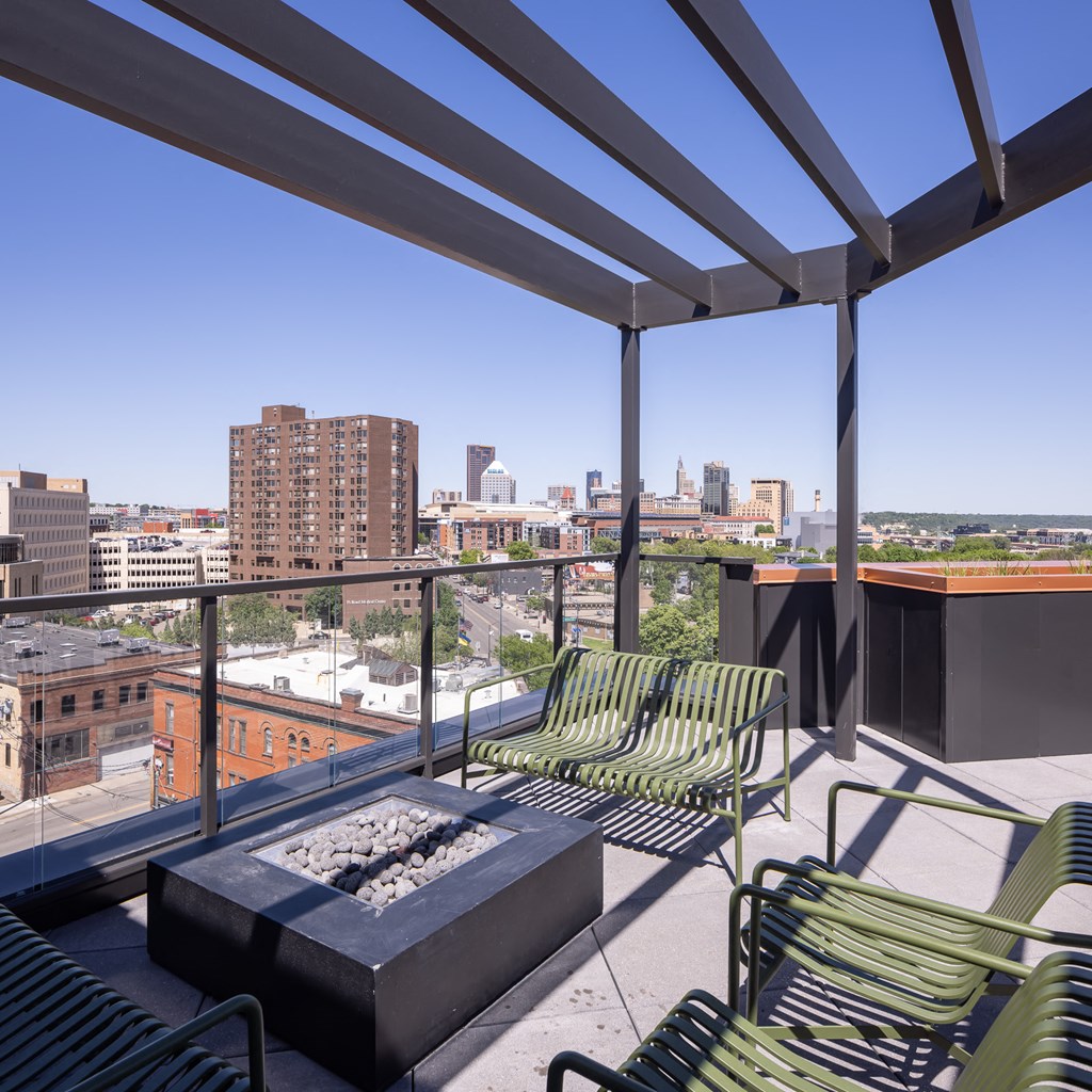 a balcony with green chairs and a fire pit and a view of the city