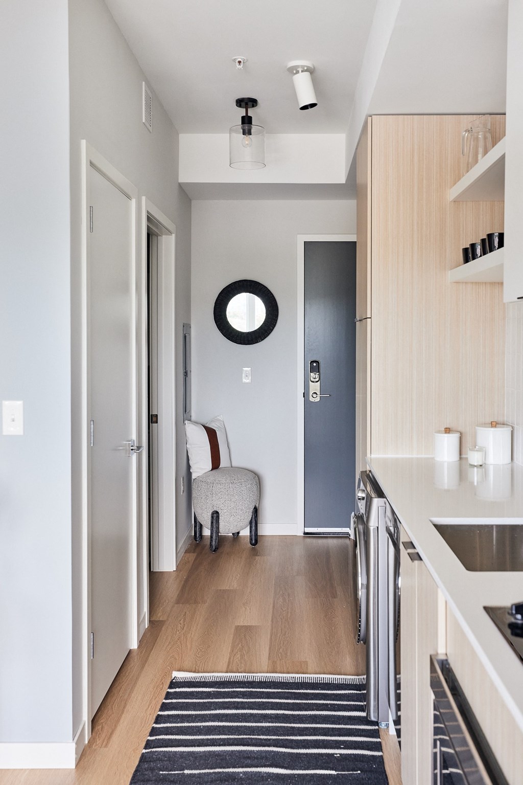 a hallway with a kitchen and a chair and a door to a living room