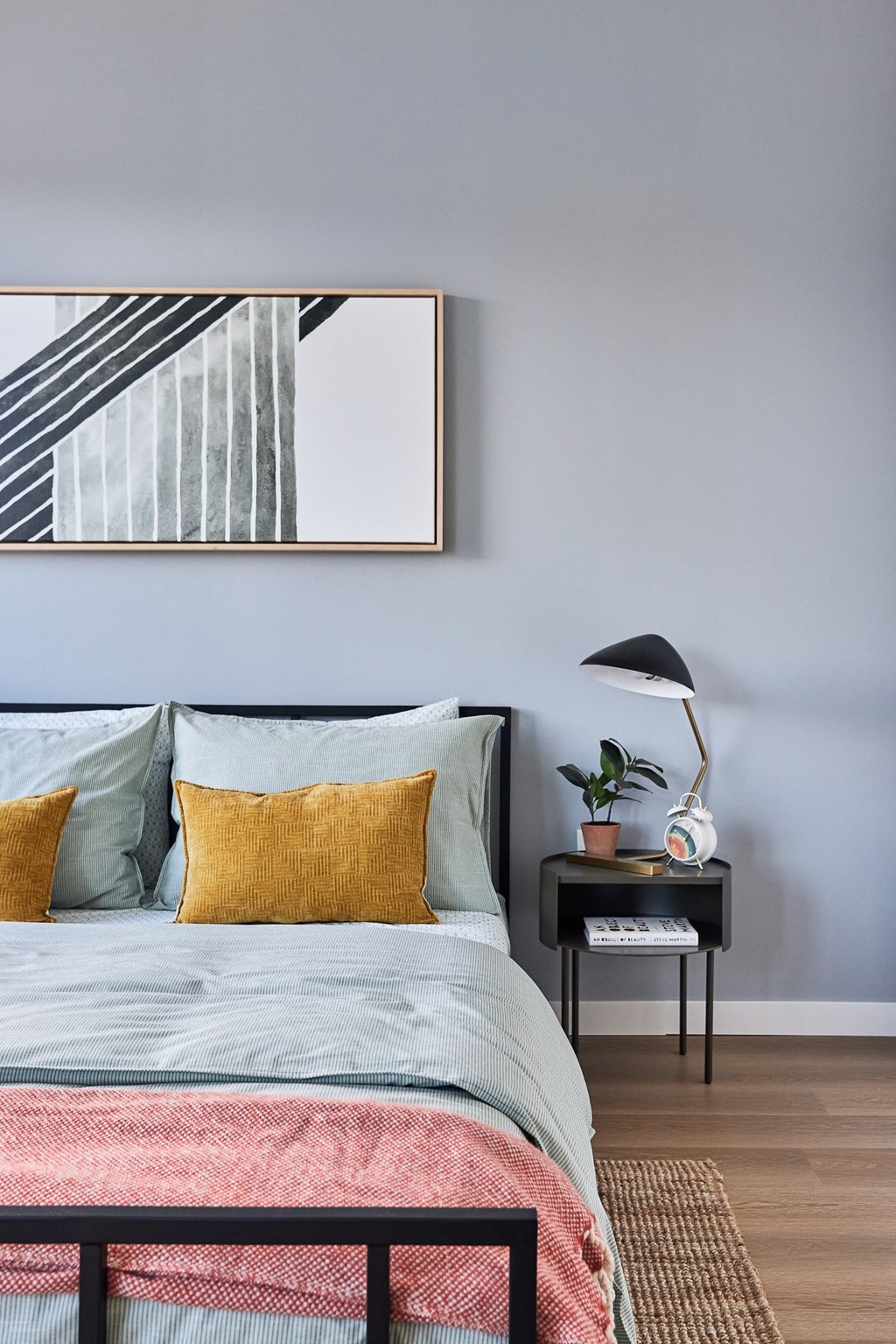 a bedroom with a bed with colorful pillows and a nightstand with a lamp