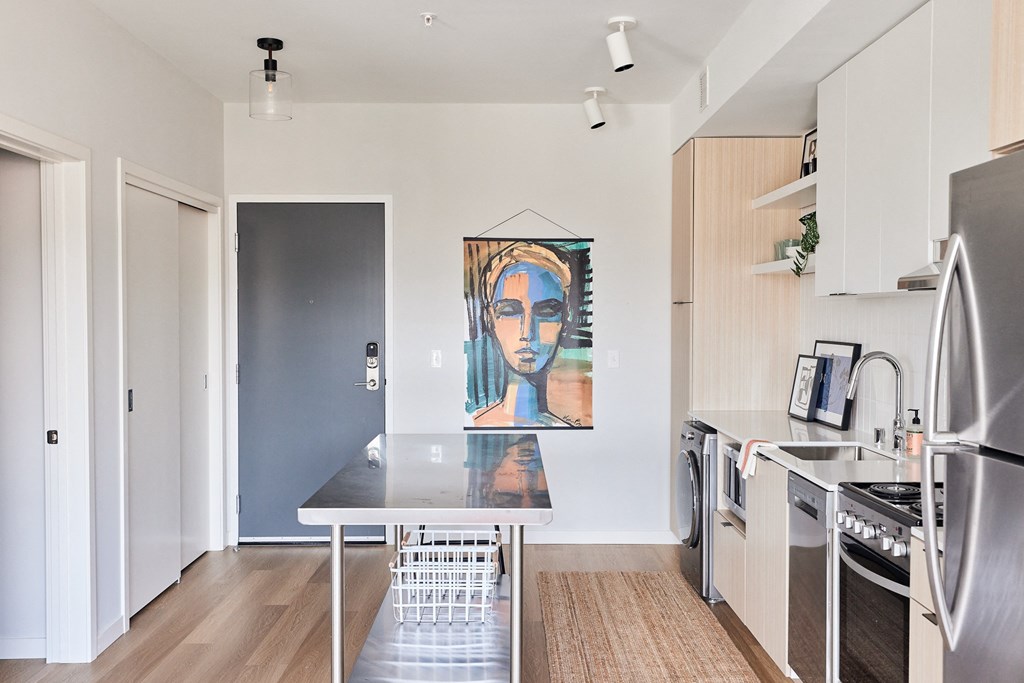 a kitchen with stainless steel appliances and a painting of a woman