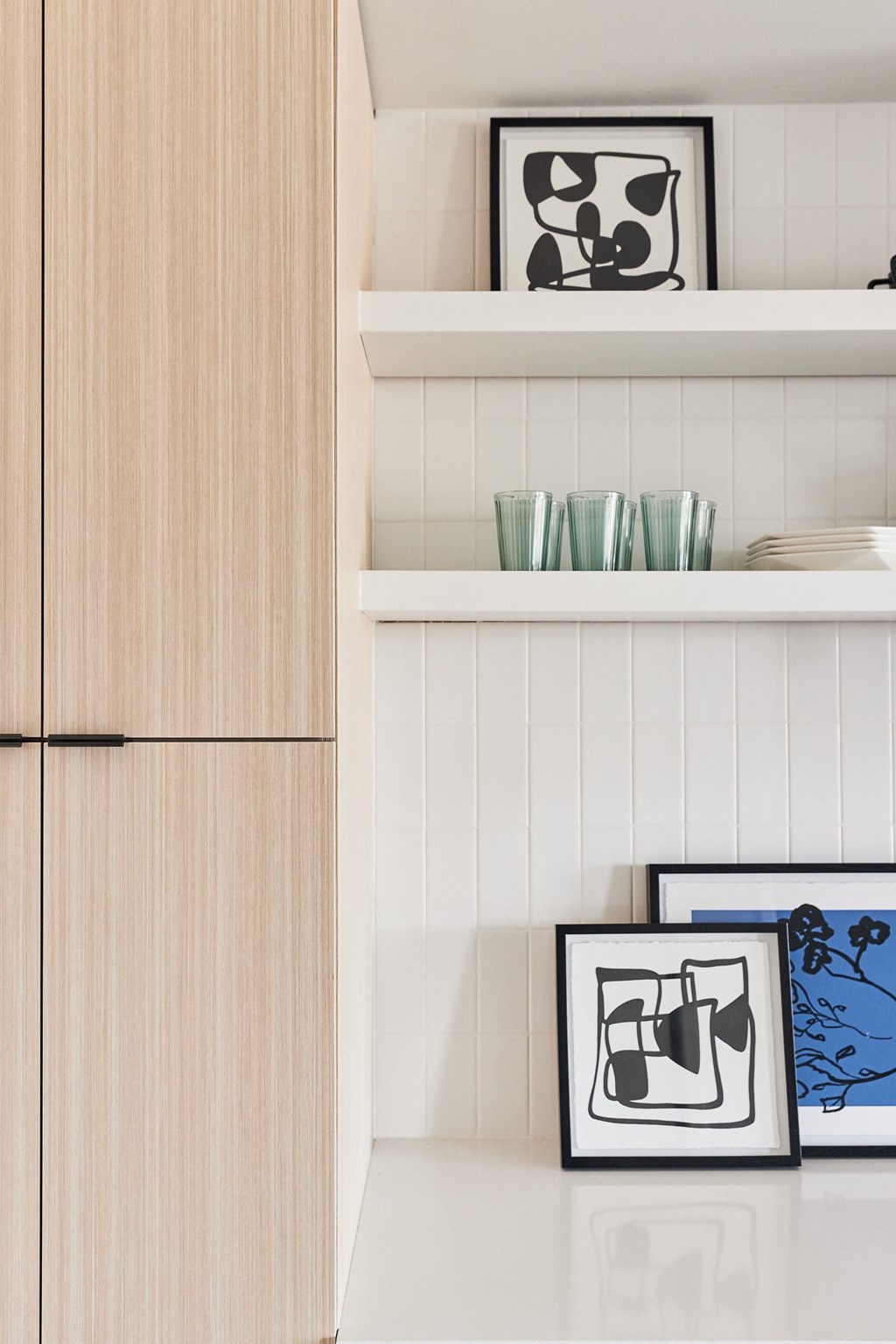 a kitchen with white cabinets and a shelf with cups and pictures