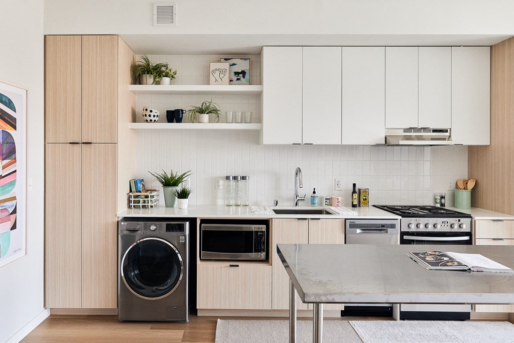 a kitchen with white cabinets and a washing machine and a table