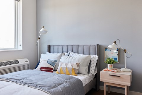 a bedroom with a bed with pillows and a nightstand with two lamps