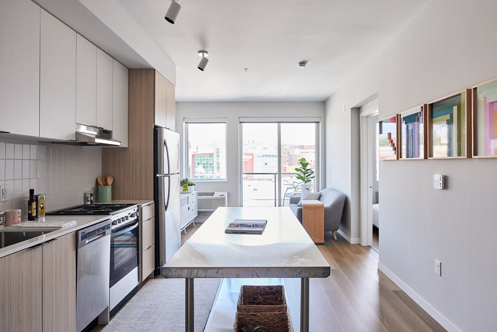 a kitchen and living room with wood floors and white cabinets