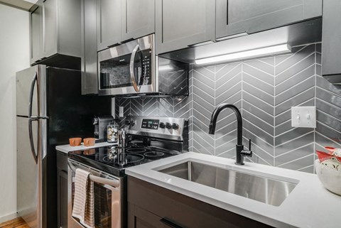 A modern kitchen with a black stove top oven and a black refrigerator.