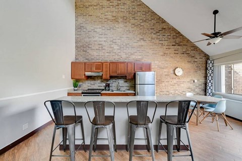 A kitchen with a brick wall and a dining table with chairs.