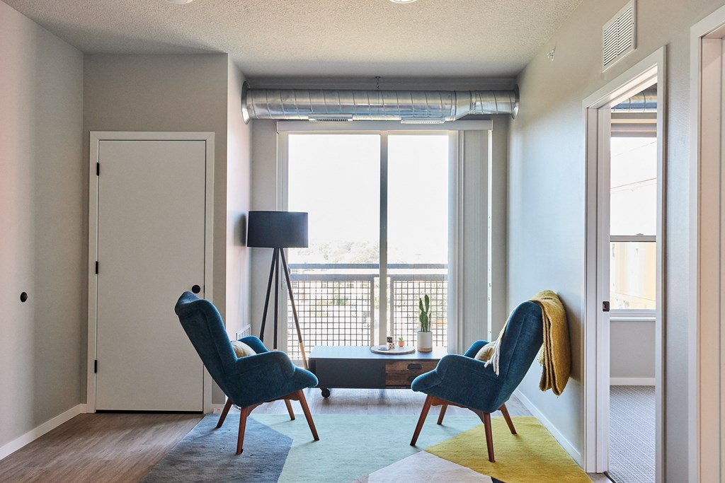 a living room with two blue chairs and a large window