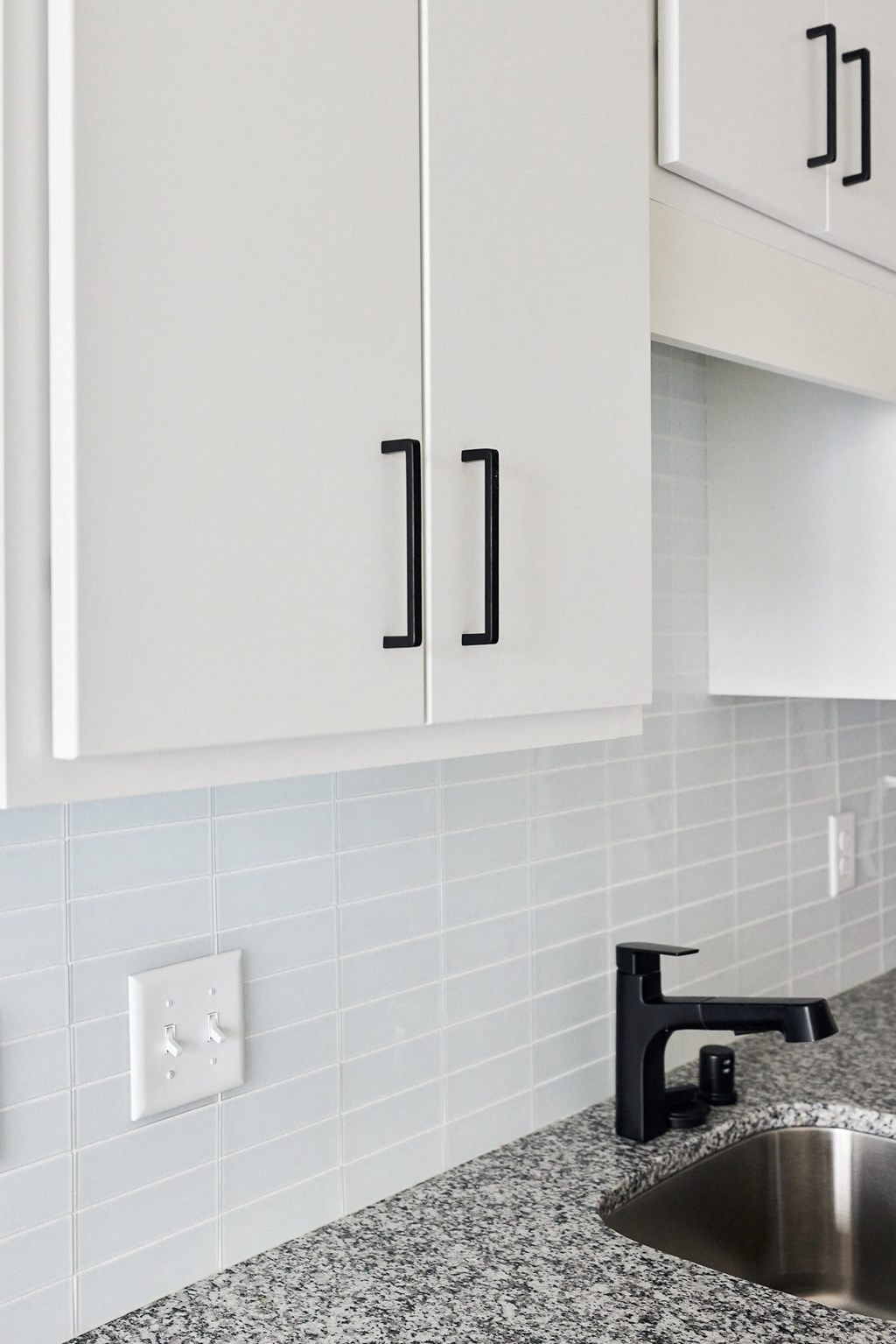 a kitchen with white cabinets and black fixtures and a sink
