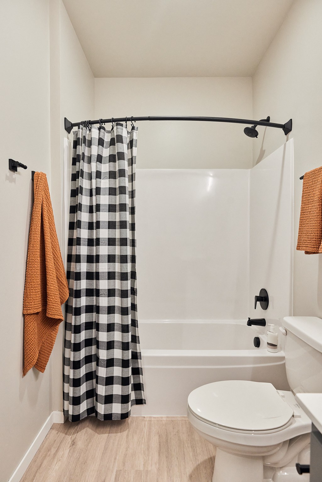 a bathroom with a toilet and a shower with a gingham shower curtain