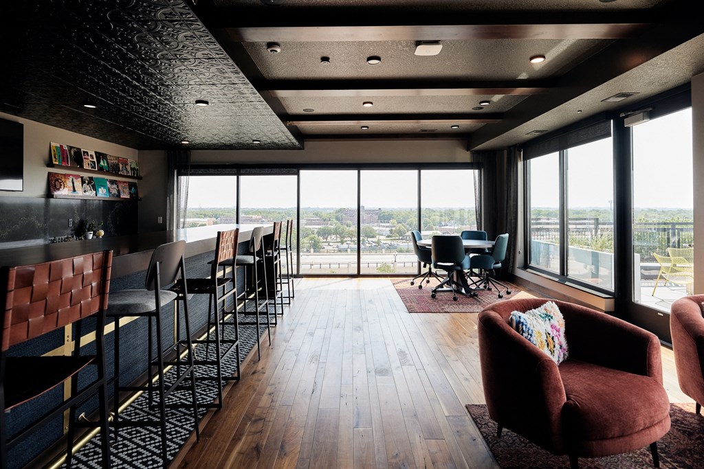 a lounge area with chairs and tables and a large window