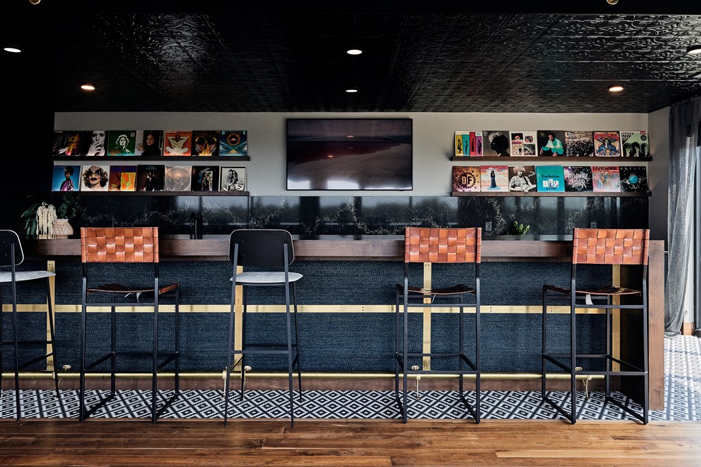 a bar with three stools and a television on the wall