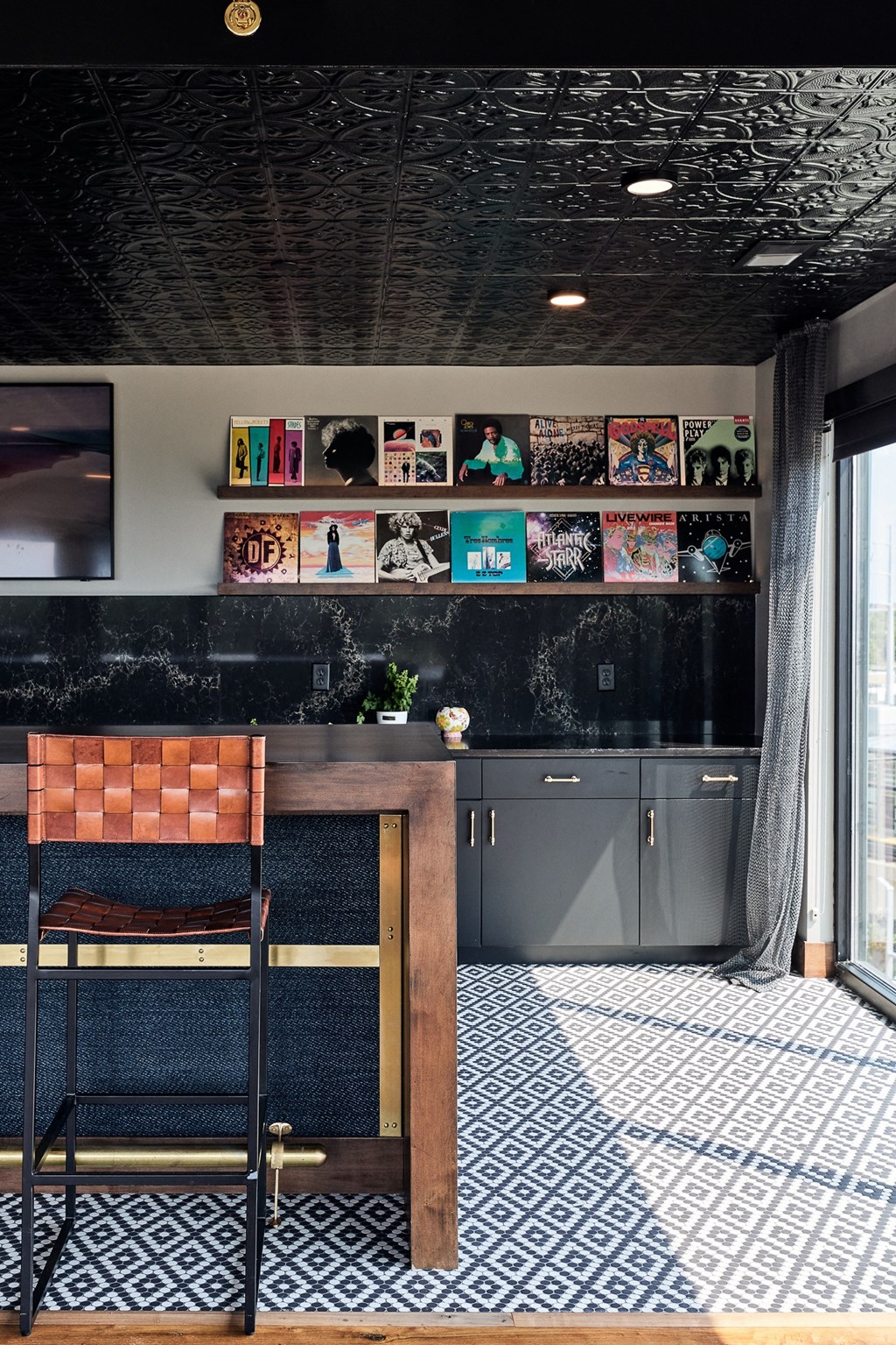 a kitchen with a table and a chair and a black and white tiled floor