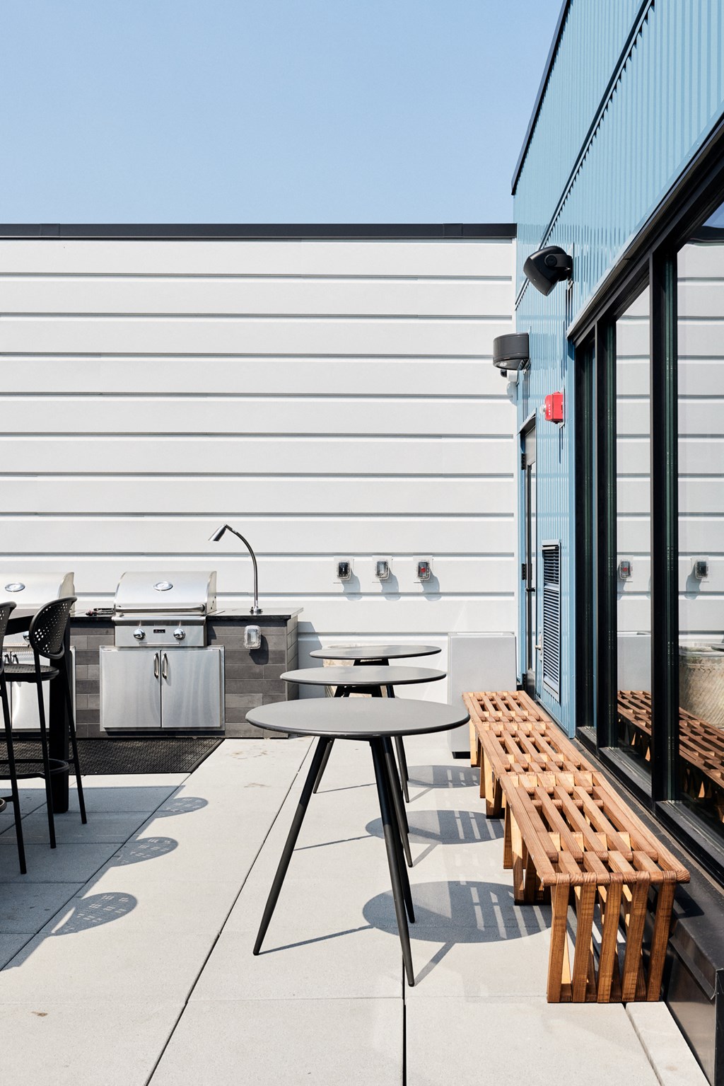 a patio with tables and chairs and a grill outside of a building