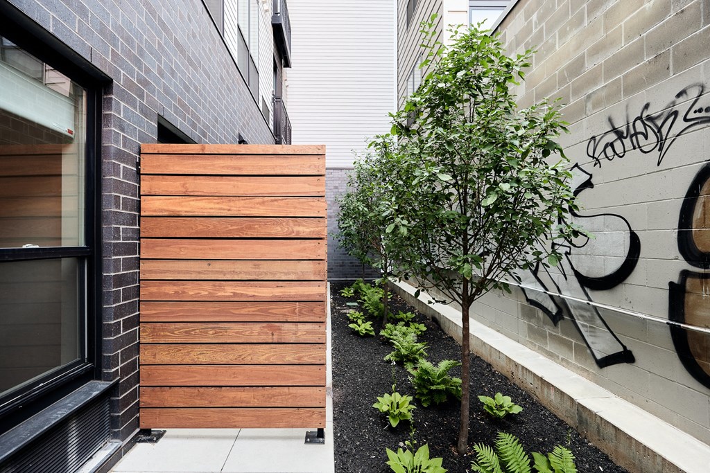 a wooden fence in front of a brick wall next to a tree