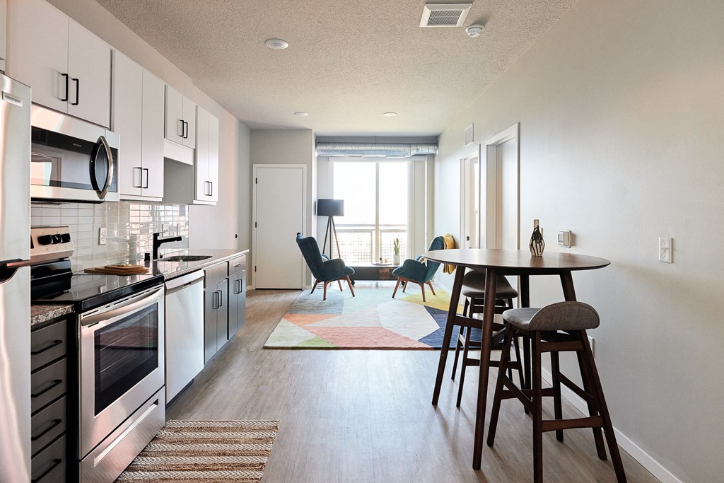 an open kitchen and living room with a dining room table and chairs and a kitchen