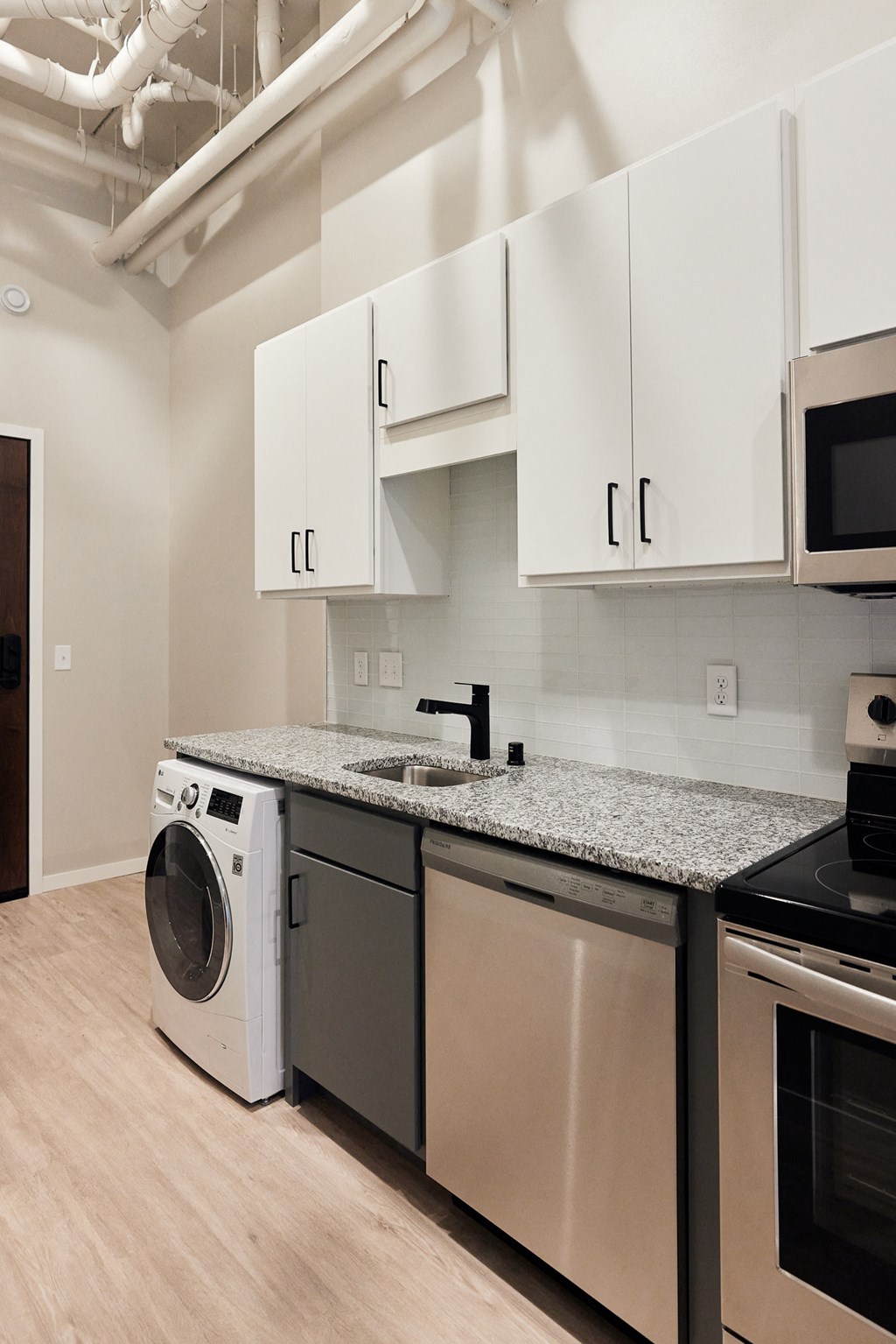 a washer and dryer in a kitchen with white cabinets and a counter top