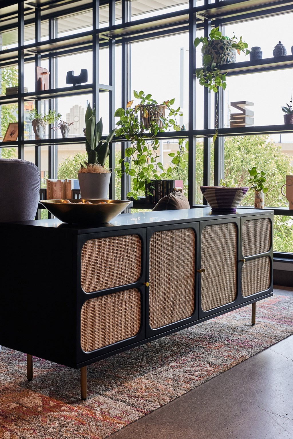 a living room with a large window and a table with plants on it