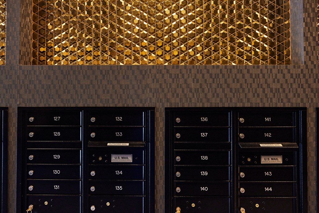 a wall of mailboxes in front of a wall with gold tiles