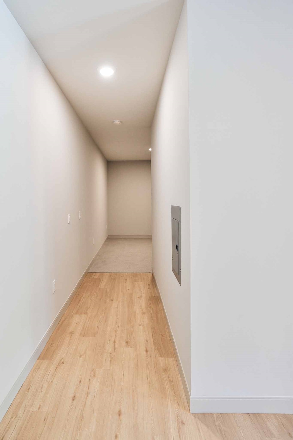 a hallway with white walls and wood floors