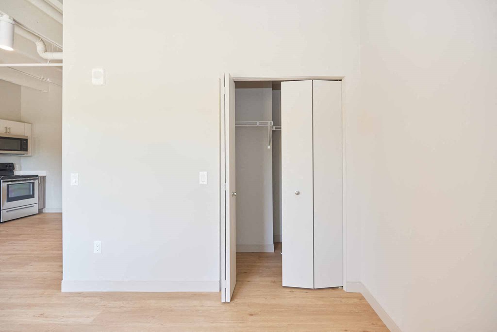a room with an open closet door and a wood floor